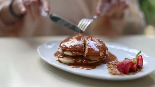 someone cutting slice of pancakes
