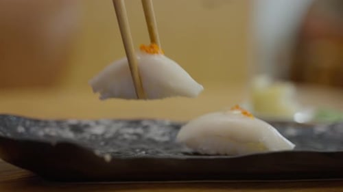 Sticks Take Sushi From Sushi Box White Fish on Sushi Rice in a Restaurant