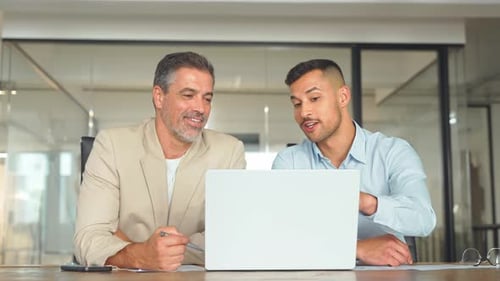 Two Busy Happy Business Men Working Together Using Laptop in Office