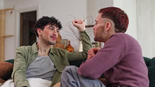 Romantic Gay Couple Embracing and Kissing on a Sofa at Home