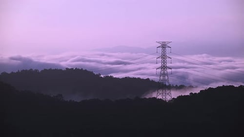 A high voltage tower and a sea of raging, tumbling clouds on a summer morning.