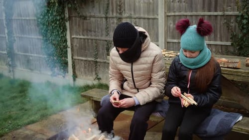 Brother and Sister Preparing Small Wooden Sticks to Feed Growing Fire Fun Filled Family Moments