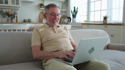 Senior Man Types on Laptop at Home