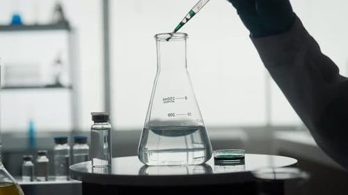Scientist Adds Green Liquid to Laboratory Flask