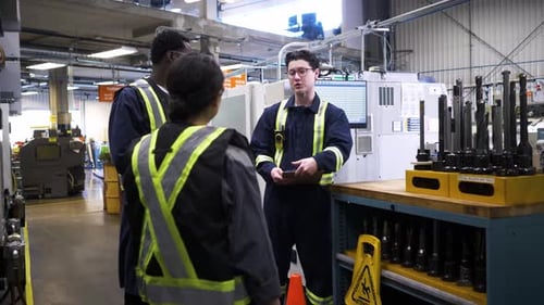 Workers In Reflective Clothing Meeting In Manufacturing Plant
