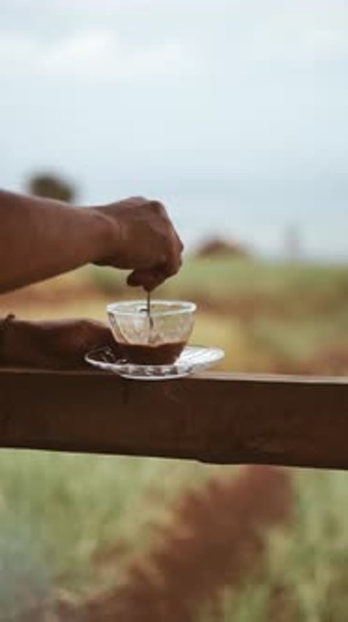 Hand stirs coffee outside