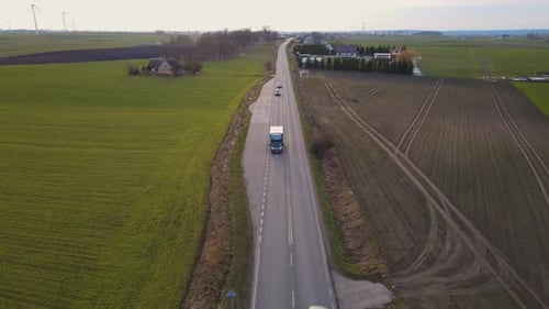 Cargo Truck Driving on Rural Road with Agricultural Field By Two Sides of Highway