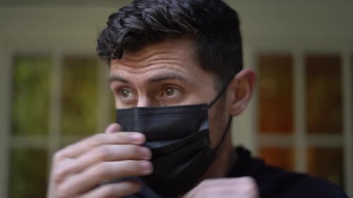 Man Puts on Disposable Face Mask Close Up