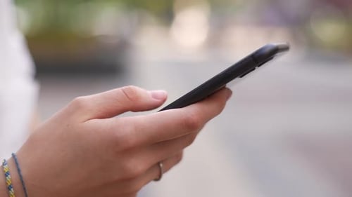 Hands Scrolling on a Black Smartphone Device