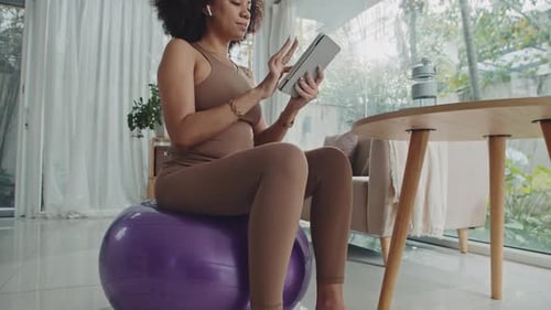 Young Woman Using Tablet While Sitting on Ball