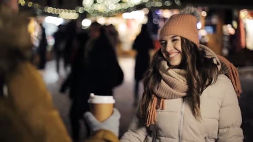 Happy young man brings coffee to his woman at christmas market on winter holidays