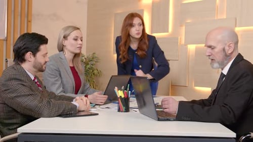 Professionals in Business Meeting at Table with Laptops