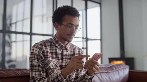 Young Adult Using Smartphone on Couch Indoors