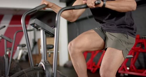 Exercising intensely, man using stationary bike for cardio workout in gym