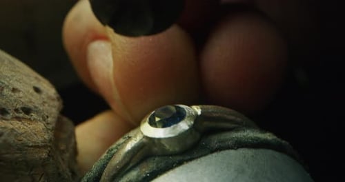 Slow motion macro of experienced goldsmith working on a handmade jewelry ring with precious gems i