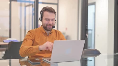 Man with Headset Working on Laptop in Office