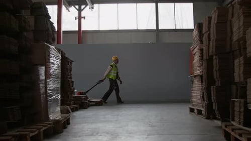 Male Worker Pulling Trolley with Cargo at Factory Warehouse