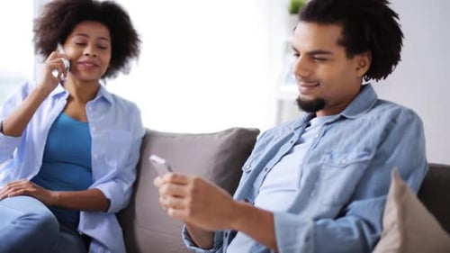 Young adults relaxing on sofa with cellphones