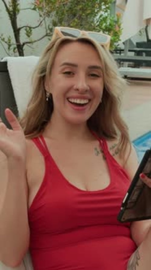 Woman in Swimsuit Using Tablet by Tropical Pool