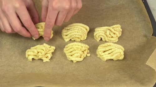 A man puts the dough on a baking sheet covered with parchment paper for baking and making cookies