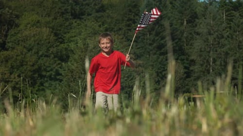 Happy Boy Running with American Flag in Field
