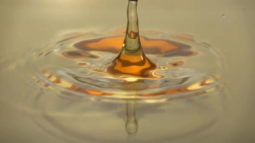 Droplets Causing Ripples in Golden Liquid