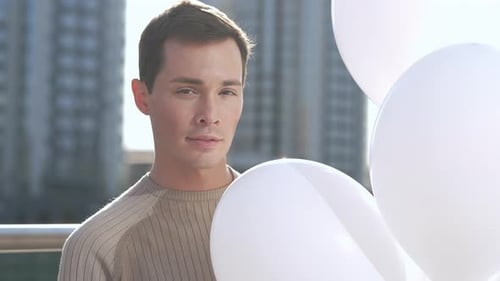 Man Holding Balloons Outside in City