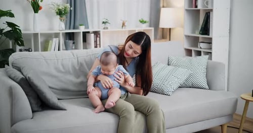 Loving Mother Plays with Baby on Couch