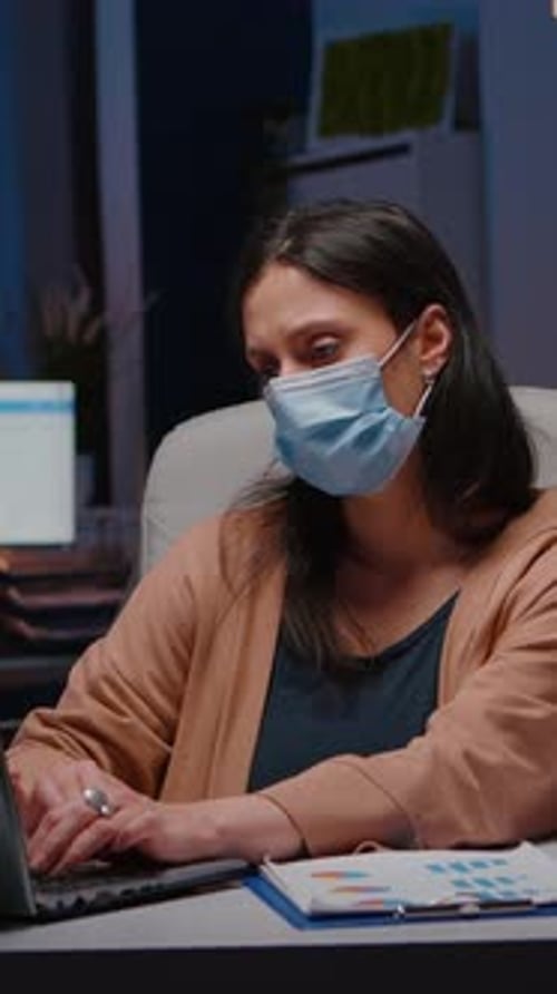 Une femme d'affaires accro au travail avec un masque facial contre la Covid-19 travaille dans un bureau de démarrage