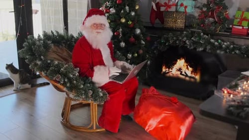 Santa Claus Using Laptop by Cozy Fireplace