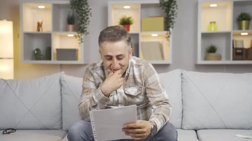 Excited Man Cheers While Reading Good News at Home