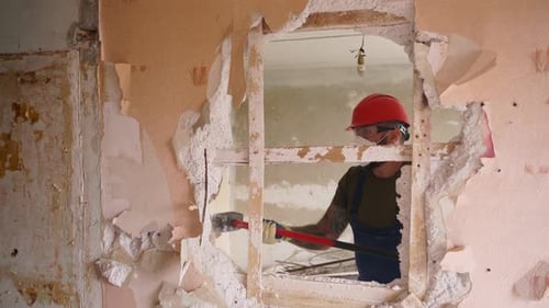 Un contratista destruye una pared con un mazo haciendo un agujero para reorganizarlo, un hombre que realiza un desmantelamiento manual