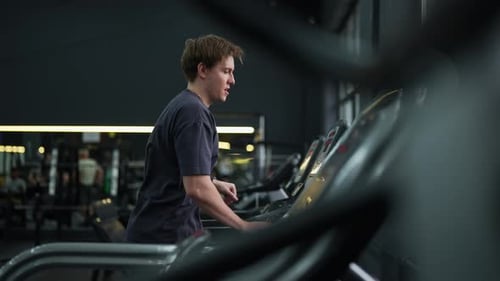 Young Man Exercising on a Treadmill in Gym