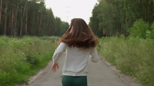 Woman Runs Along Road Past Forest Bushes