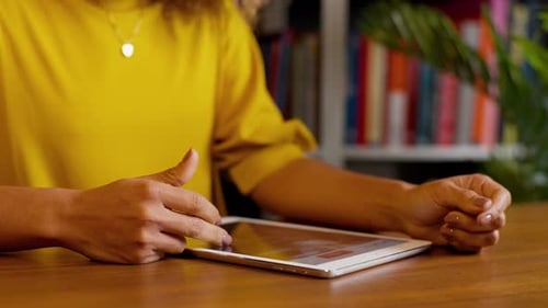 Frau scrollt auf Tablet am Schreibtisch aus nächster Nähe
