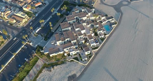 A 4K aerial drone shot of beachfront condos pulls back to reveal the ocean and a pier.