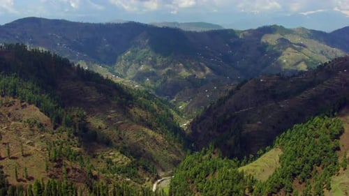 Drone au-dessus de la forêt de montagne jusqu'à la vallée sur la montagne, montrant des routes et des maisons sur les montagnes