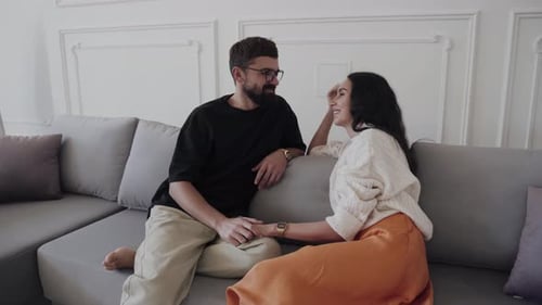 Attractive Couple Smiling and Holding Hands on Couch