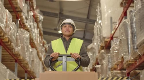 Female Warehouse Worker Carrying Hand Pallet Truck along Aisle