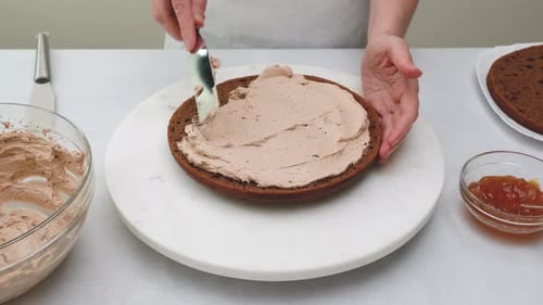 Hands Spread Icing on Chocolate Cake Layer