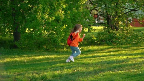 Camera Movement on Happy Preschooler with School Backpack Runs and Laughs in Green Summer Park