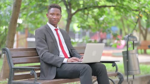 Young Man Working on Laptop in Park Smiling