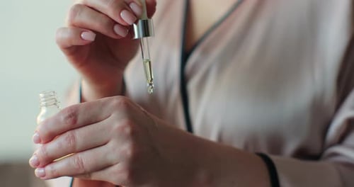 Woman Applying Skincare Oil to Her Hands