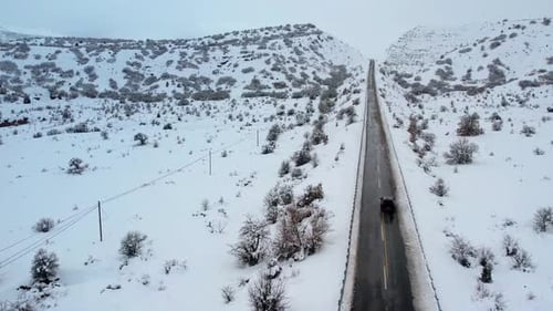 Car Driving on Snowy Mountain Road in Winter Landscape