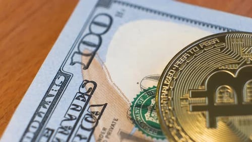 Gros plan d'une pièce de monnaie cryptographique Bitcoin brillante en métal sur des billets en dollars américains
