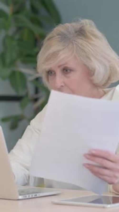 Old Woman Shocked by Loss on Laptop and Documents, Paperwork, vertical video