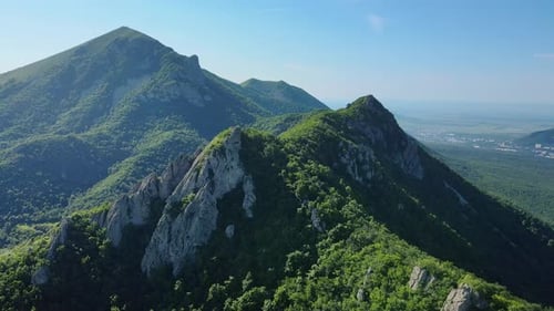 A Scenic Aerial View of a Treecovered Mountain Under a Sunny Sky
