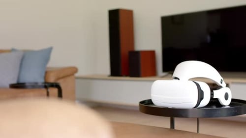 A virtual reality headset rests on a table in a modern living room
