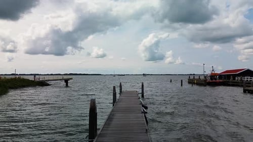 A peaceful lakeside scene with a wooden pier stretching into the water, cloudy sky overhead