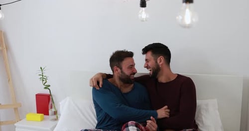 Affectionate Men Embracing and Laughing in Bedroom